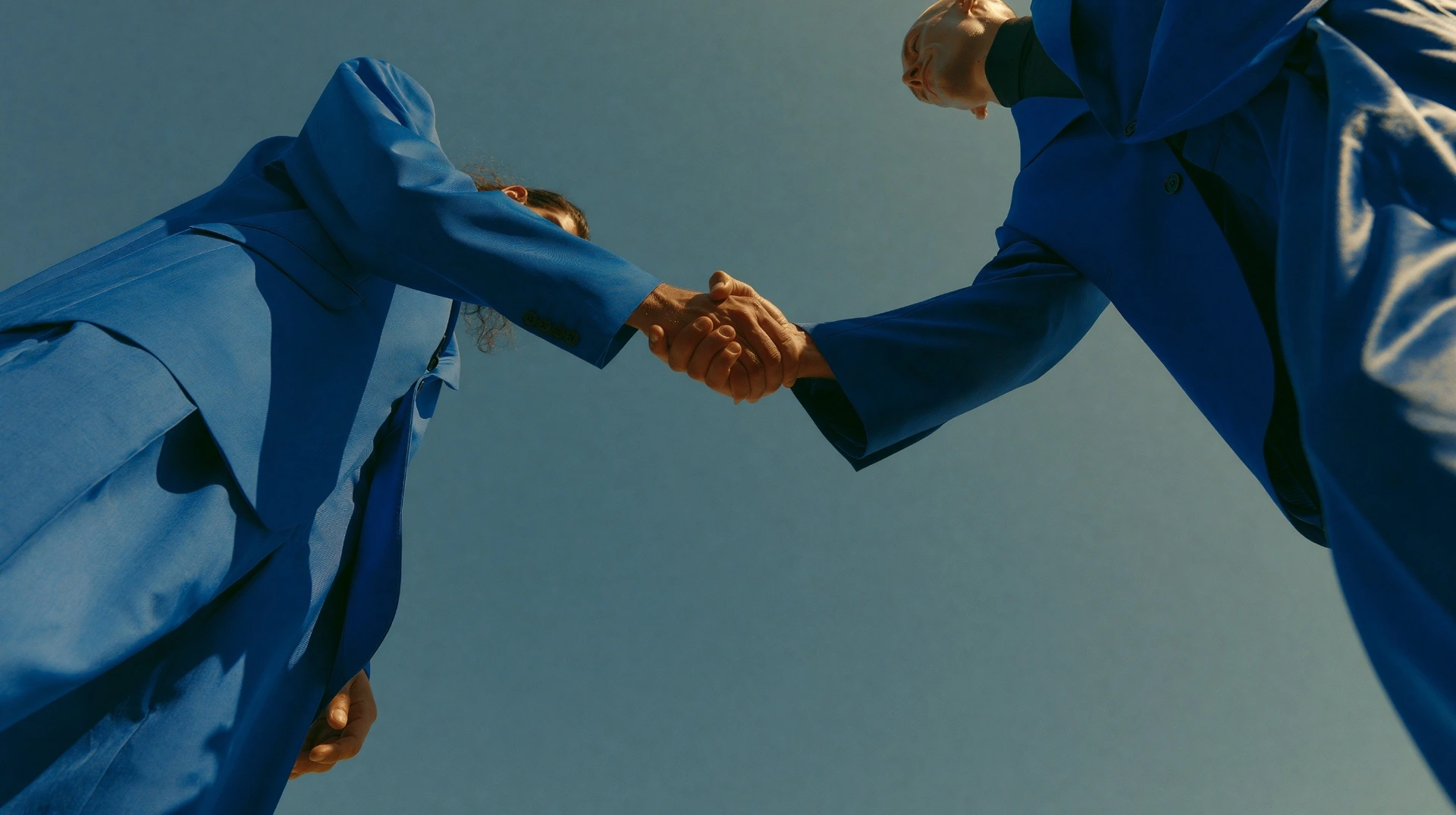Two executives in cobalt suits shaking hands